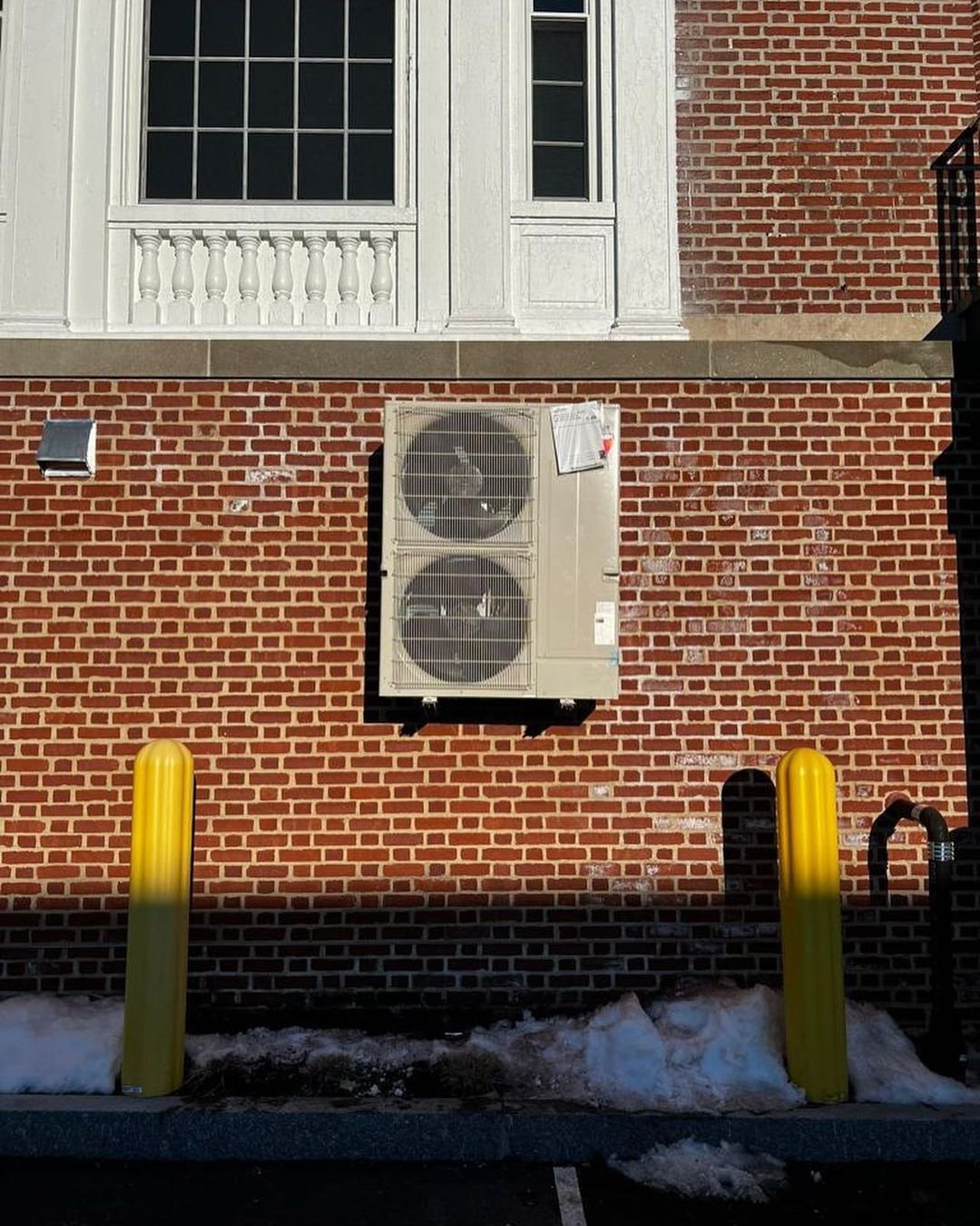 Air conditioning condenser installed on a brick wall in Boston